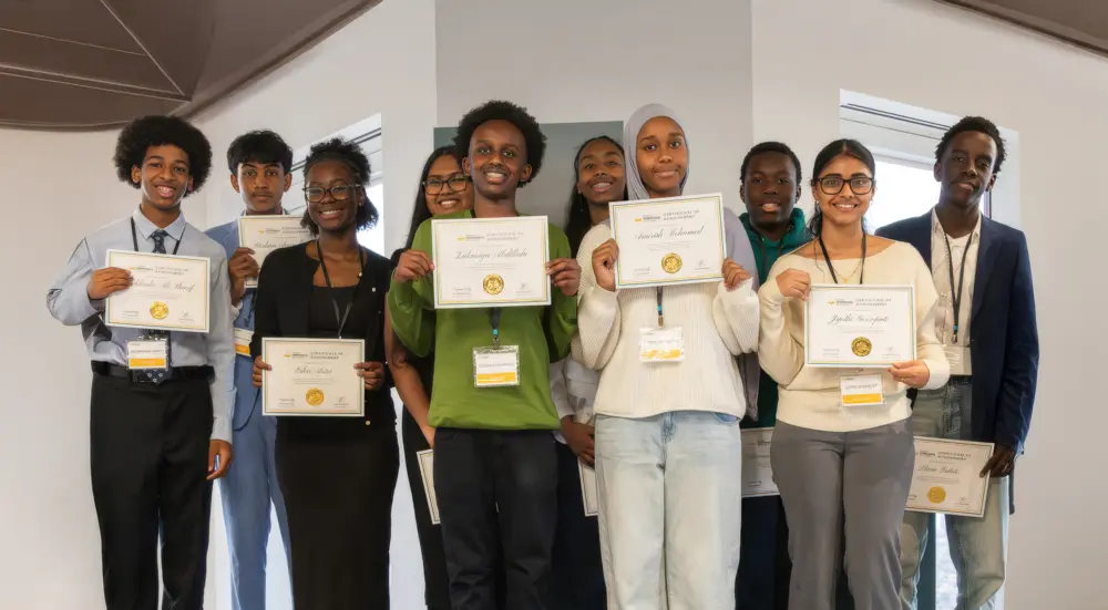 A group of young people smiling and holding certificates while posing indoors for a photo.