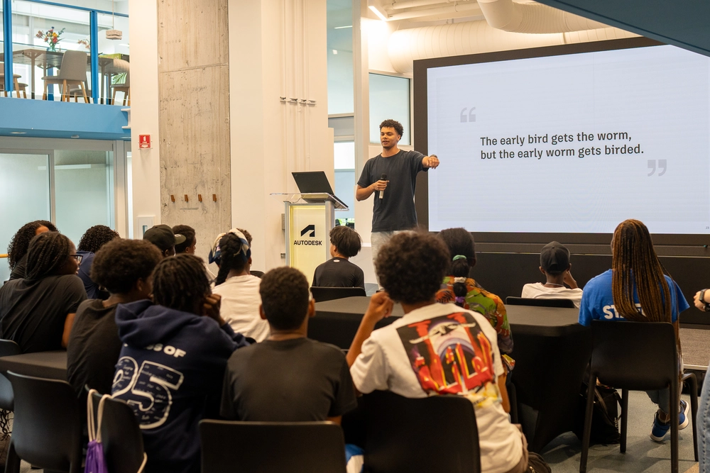 A speaker addresses a seated audience; a screen displays, The early bird gets the worm, but the early worm gets birded.
